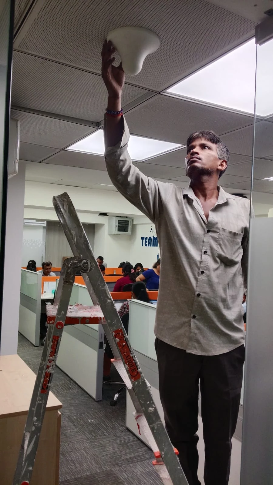 Technician installing indoor signal antenna on office ceiling